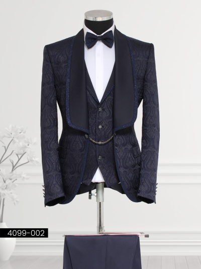 Navy blue brocade suit for men featuring intricate paisley patterns, satin shawl lapel with glittering trim, matching waistcoat with chain detail, and tailored trousers.