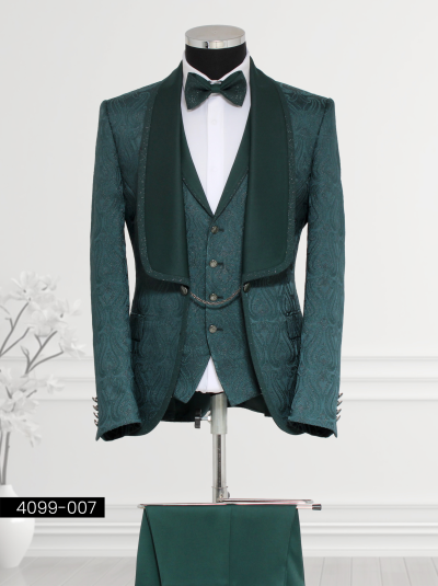 Emerald green brocade suit for men featuring paisley patterns, satin shawl lapel blazer, matching waistcoat with silver buttons and chain detail, and tailored trousers.