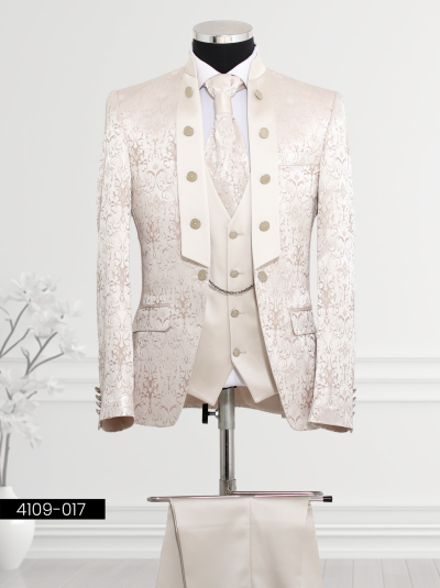 Ivory suit designed for men features floral brocade patterns, mandarin collar design, wide lapel with decorative buttons, double-breasted waistcoat with silver buttons and chain detail, and matching trousers.