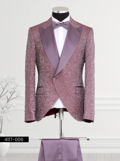 Plum tuxedo featuring floral brocade patterns, satin peak lapel design, single-button closure with black-trimmed welt pockets, matching bow tie, and tailored trousers.