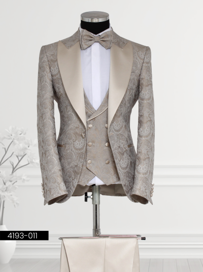 Men’s beige tuxedo suit with satin lapels, paisley vest, and bow tie—ideal for formal occasions.
