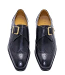 Black monk strap shoes with brogue detailing, gold buckle, pointed toe, and tan interior.